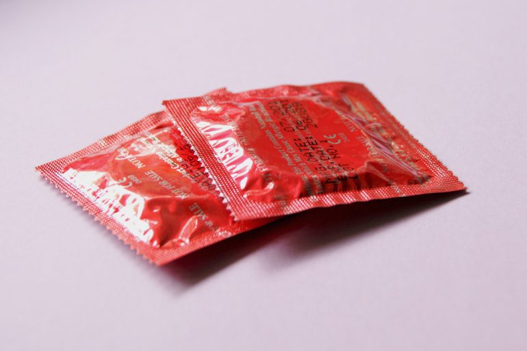 To røde kondomer ligger på et rødt og hvidt bord