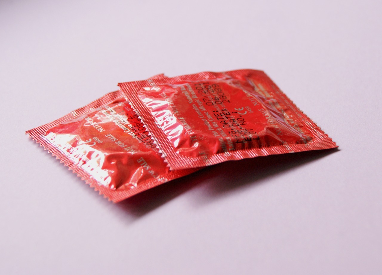 To røde kondomer ligger på et rødt og hvidt bord
